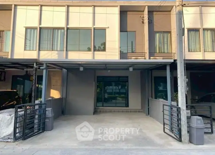 Modern townhouse exterior with gated parking area and large windows.