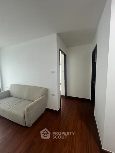 Modern living room with sleek wooden flooring and cozy gray sofa, ideal for contemporary urban living.