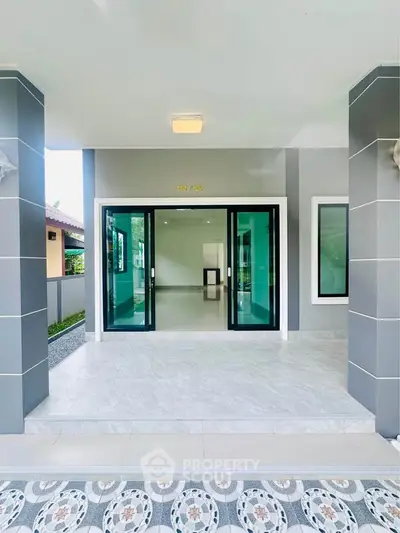 Modern entrance with sleek glass doors and tiled flooring in a contemporary home.