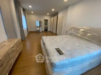 Spacious bedroom with new furniture and hardwood floors in modern apartment.