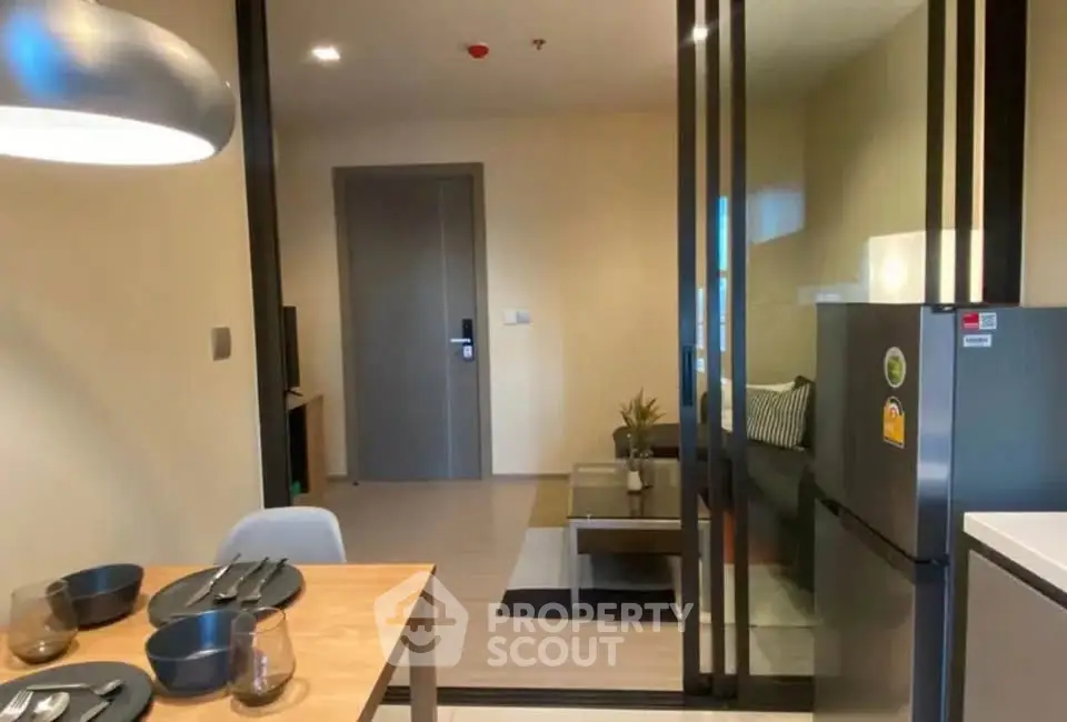 Modern apartment interior with dining area and cozy living room, featuring sleek sliding glass doors.