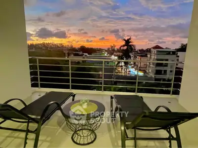 Stunning sunset view from a modern balcony with lounge chairs and table, perfect for relaxation.