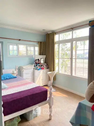 Charming bedroom with large windows and cozy decor, perfect for relaxation and natural light.