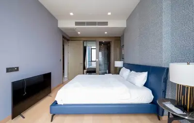 Modern bedroom with sleek design and luxurious blue bed in a high-end apartment.