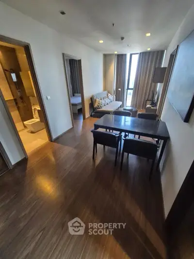 Modern apartment interior with open living and dining area, featuring wooden flooring and stylish decor.