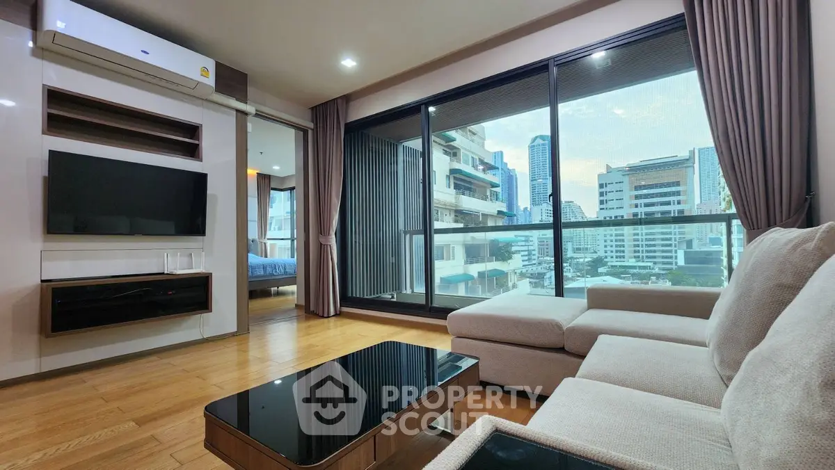 Modern living room with city view, large windows, and stylish furniture