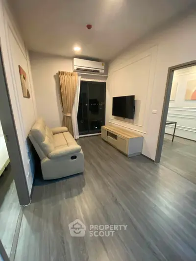 Modern living room with sleek flooring, cozy sofa, and wall-mounted TV, perfect for relaxation.