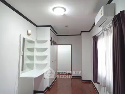 Spacious bedroom with built-in wardrobe and air conditioning, featuring elegant wooden flooring and ample natural light.
