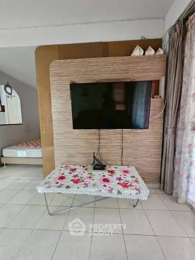 Cozy living room with mounted TV and floral tablecloth, perfect for relaxation.