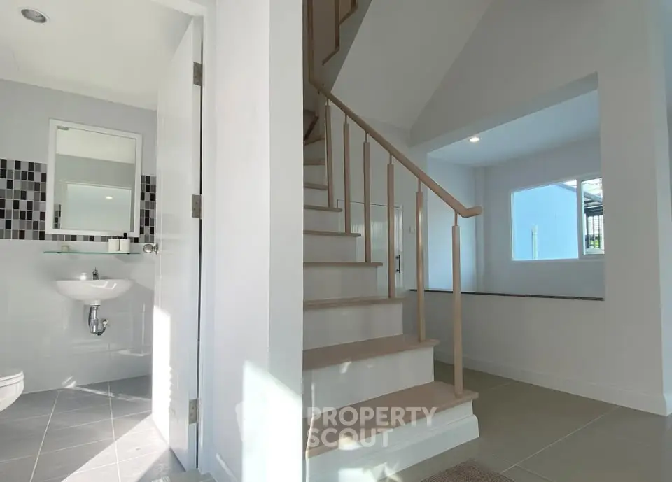 Bright interior with modern staircase and bathroom, showcasing sleek design and natural light.