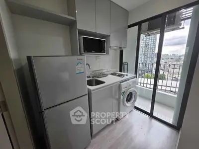 Modern compact kitchen with appliances and balcony view in urban apartment