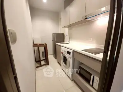 Modern kitchen with sleek appliances and compact design, featuring washing machine and microwave.