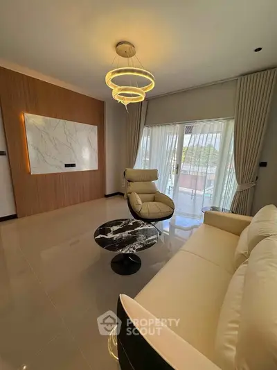 Elegant living room with modern lighting, marble accent wall, and plush seating, offering a cozy and stylish ambiance.