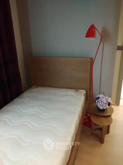 Cozy bedroom with wooden bed frame and stylish red lamp