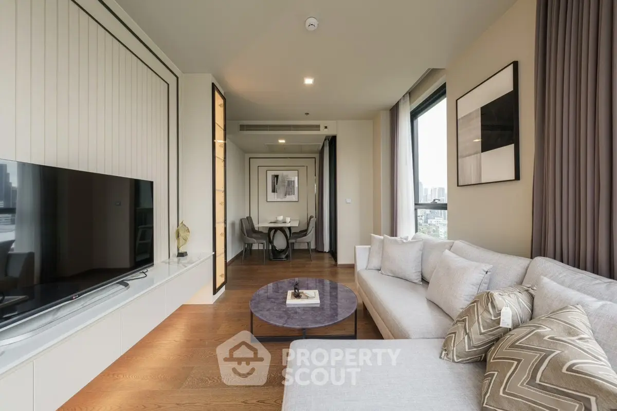 Modern living room with stylish decor and large windows offering city views.