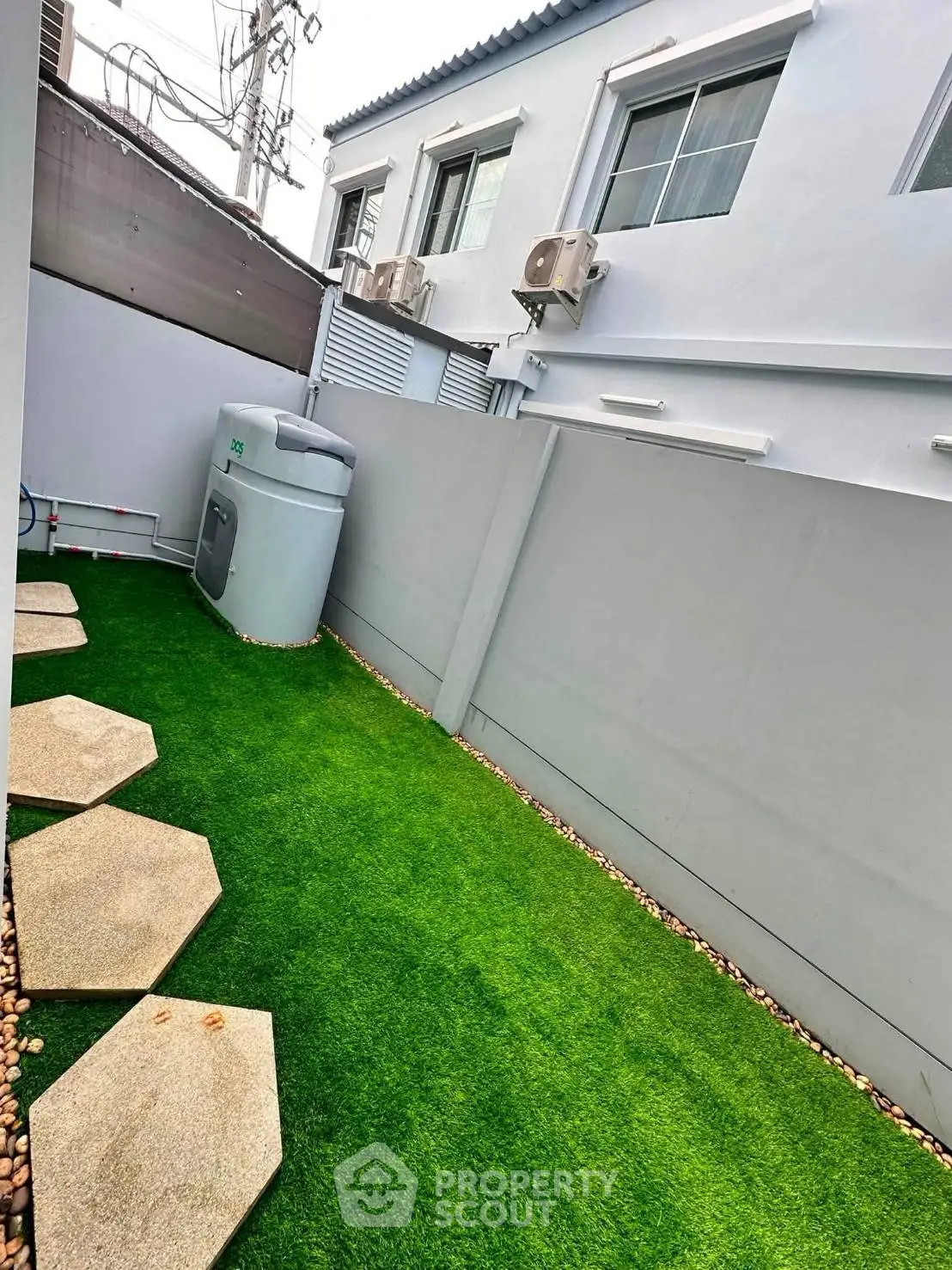 Charming small garden with artificial grass and modern exterior design, perfect for urban living.