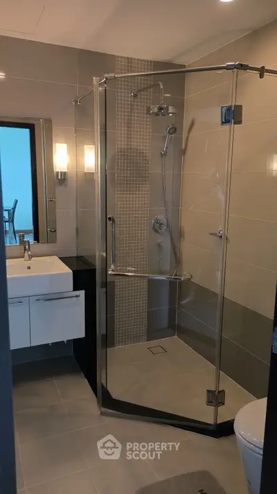 Modern bathroom with glass shower and sleek vanity in contemporary home.