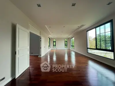 Spacious living room with hardwood floors and large windows offering natural light.