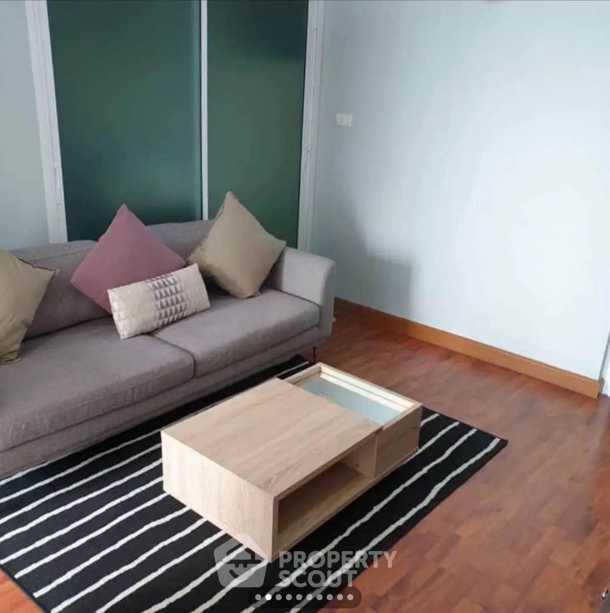 Modern living room with stylish sofa and wooden coffee table on striped rug.