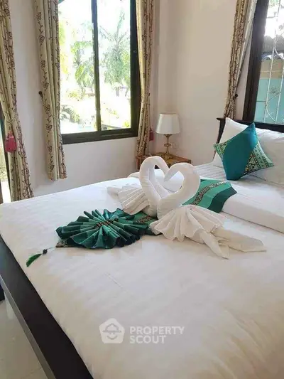 Elegant bedroom with decorative towel swans and lush garden view.