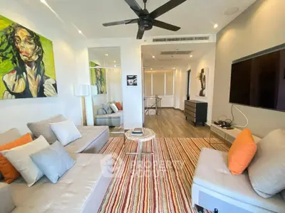 Modern living room with stylish decor and vibrant artwork, featuring cozy seating and a ceiling fan.