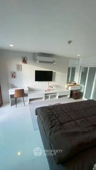 Modern bedroom with sleek furniture and wall-mounted TV, featuring a cozy workspace and stylish decor.