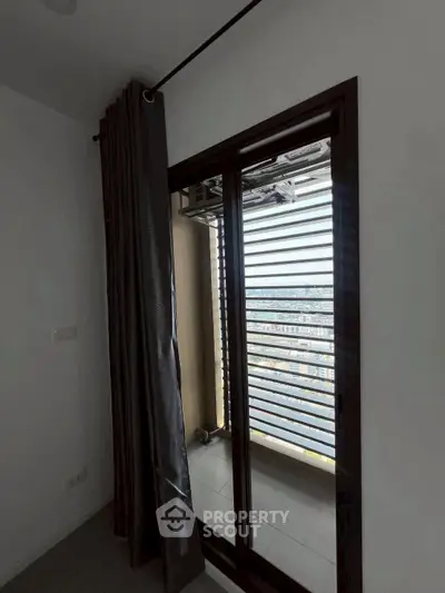 Modern apartment balcony with city view and sleek sliding doors.