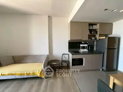 Modern open-layout living room with compact kitchen and cozy sofa, perfect for urban living.