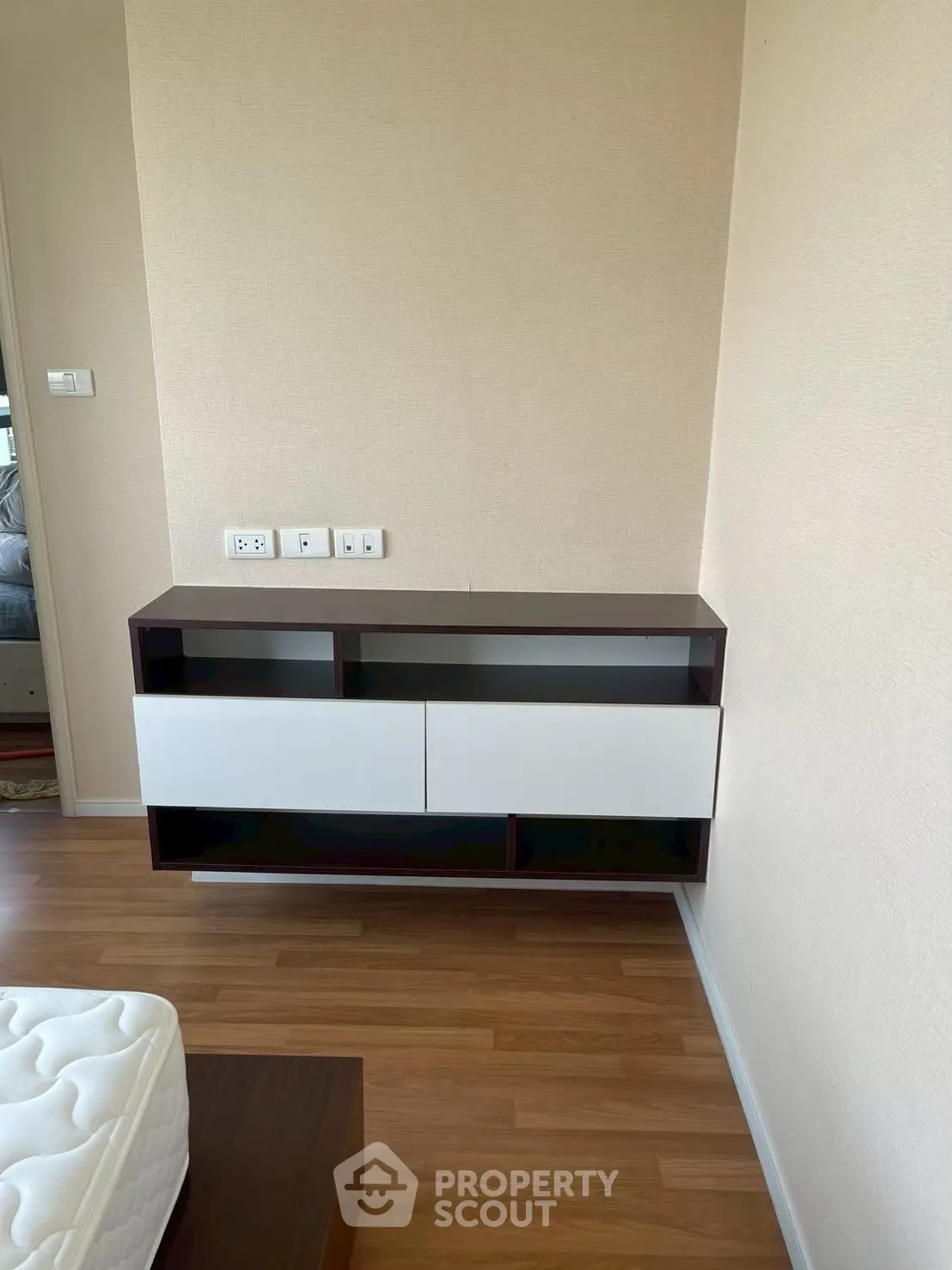 Modern bedroom with floating storage unit and hardwood flooring