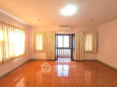 Spacious sunlit room with large windows and balcony access, perfect for a cozy living space.