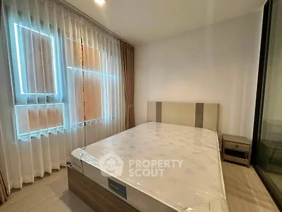 Spacious bedroom with large window and modern furnishings in a stylish apartment.
