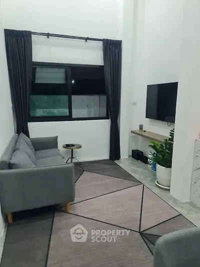 Modern living room with sleek furniture and large window, perfect for cozy evenings.