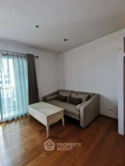 Cozy living room with wooden flooring and elegant sofa near balcony.
