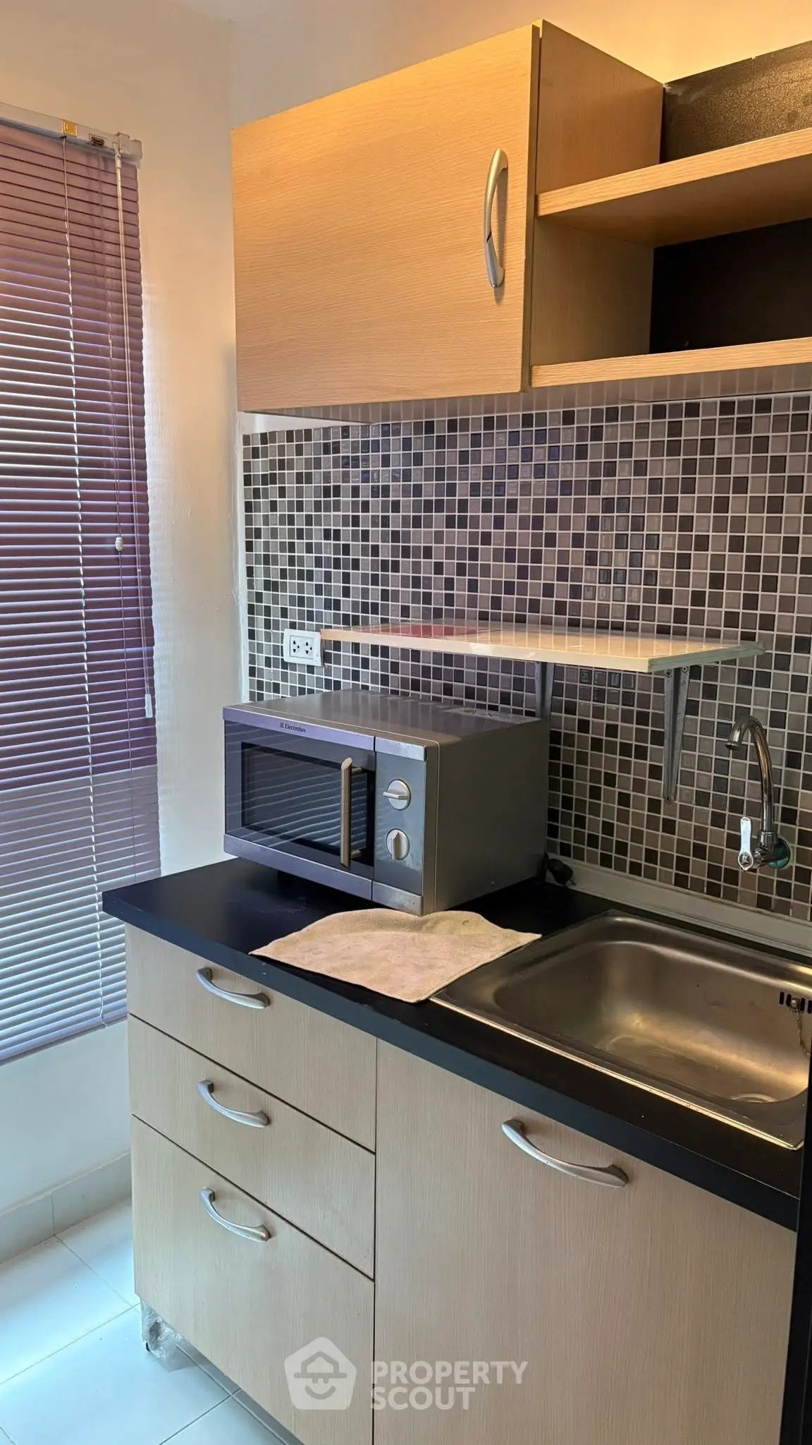 Compact kitchen with modern cabinetry and microwave, ideal for efficient cooking space.