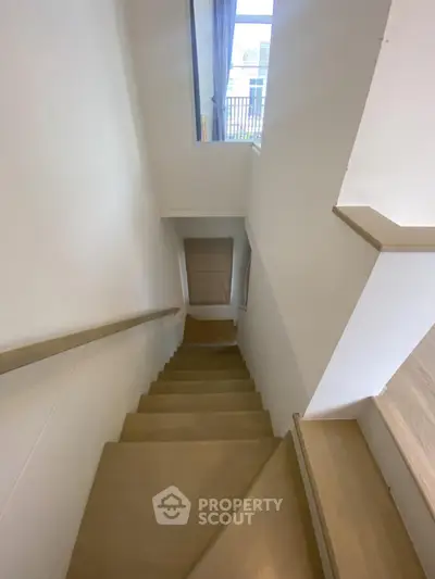 Modern staircase with wooden steps and white walls in a bright home interior
