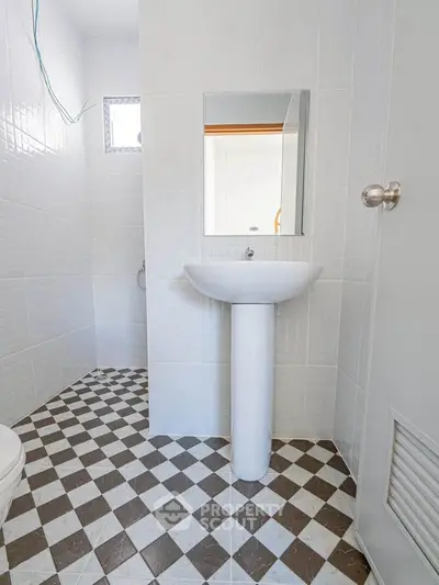 Modern minimalist bathroom with pedestal sink and checkered tile flooring.