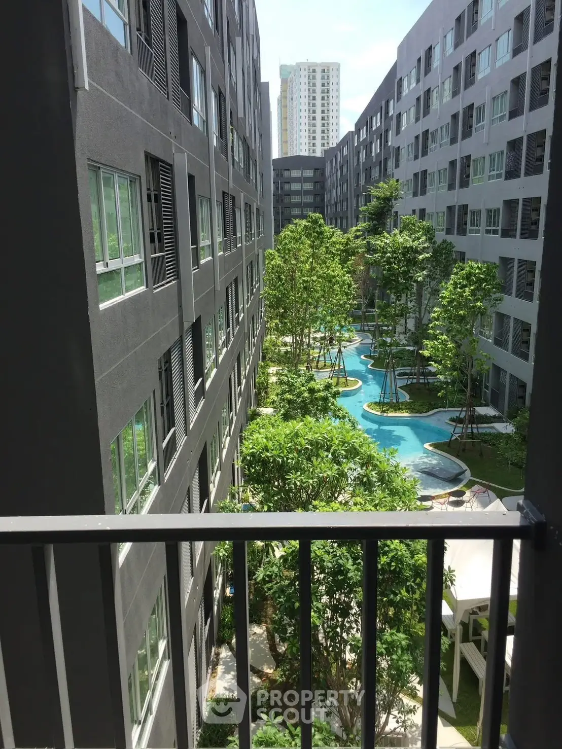 Modern apartment complex with lush garden and pool view from balcony.
