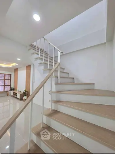 Modern staircase with sleek design leading to a bright living area with stylish decor.