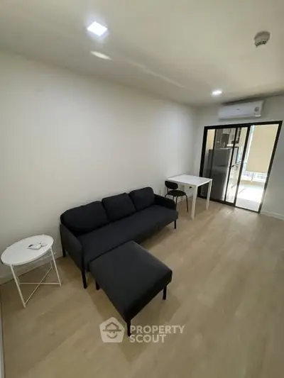 Modern living room with sleek black sofa and dining area in a minimalist apartment.
