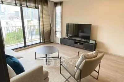 Modern living room with large TV, stylish furniture, and balcony view.