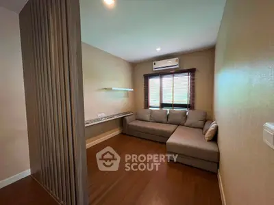 Cozy living room with sectional sofa and air conditioning, featuring warm wooden flooring and modern blinds.