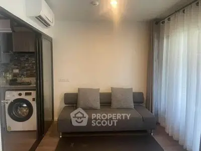 Modern living room with sofa and washing machine in open layout apartment.