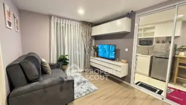 Modern living room with cozy sofa and wall-mounted TV, adjacent to sleek kitchen.