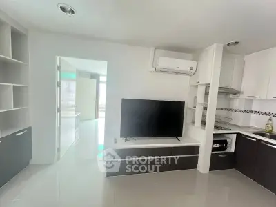 Modern living room with sleek TV setup and open kitchen layout