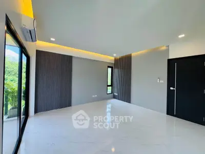 Spacious modern living room with large windows and sleek design, perfect for natural light and comfort.