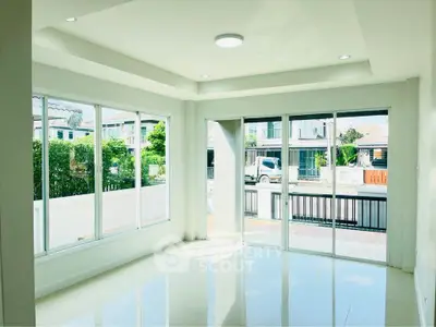Bright and spacious living room with large windows and modern design, offering a view of the neighborhood.
