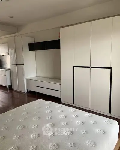 Spacious bedroom with modern white furniture and ample storage space.