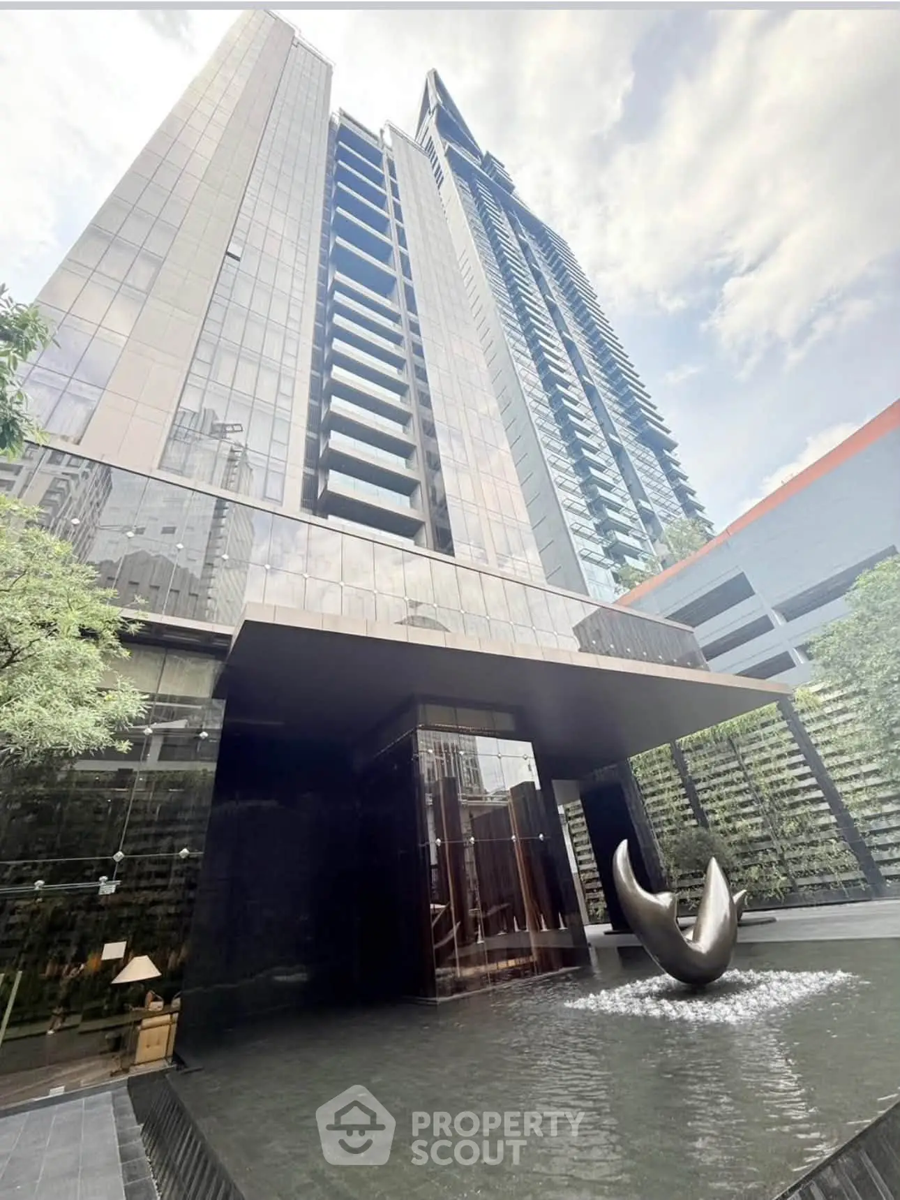 Stunning modern high-rise building with sleek architecture and elegant entrance fountain.
