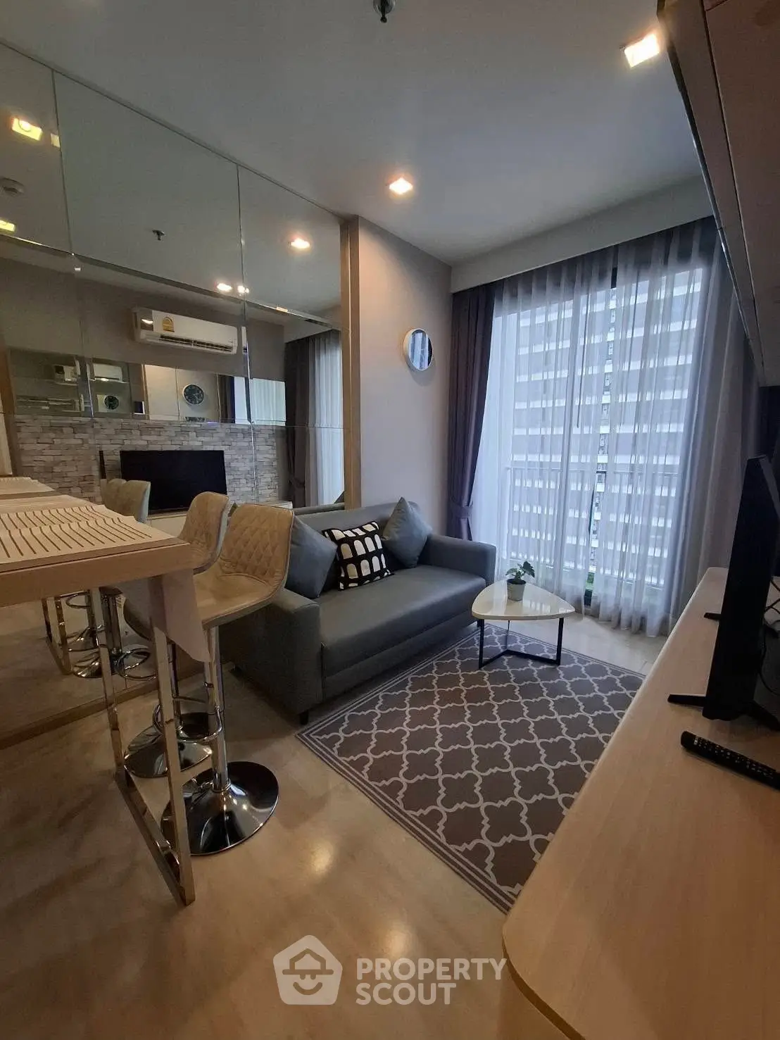 Modern living room with stylish decor and natural light, featuring a cozy sofa and elegant bar stools.