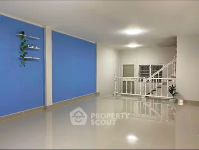 Spacious modern living room with glossy tiled floors and blue accent wall